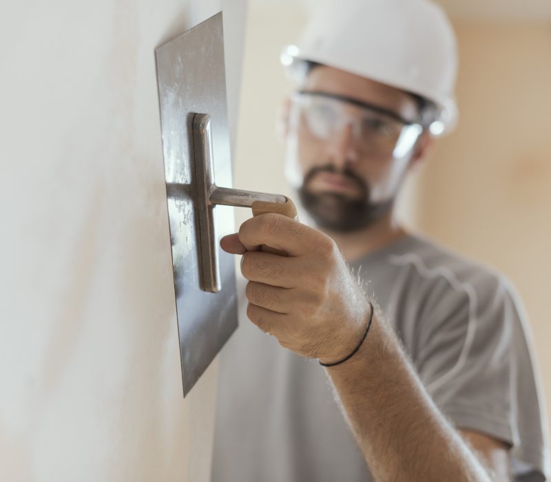 Professional craftsman applying plaster with a trowel, home renovation concept