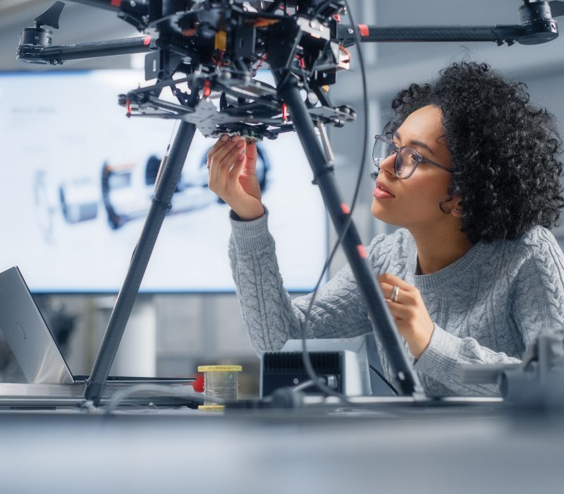 Concentrated Black Female Engineer Writing Code. Developing Software for Modern Drone Control in the Research Center Laboratory. Technological Breakthrough in Flight Industries Concept.