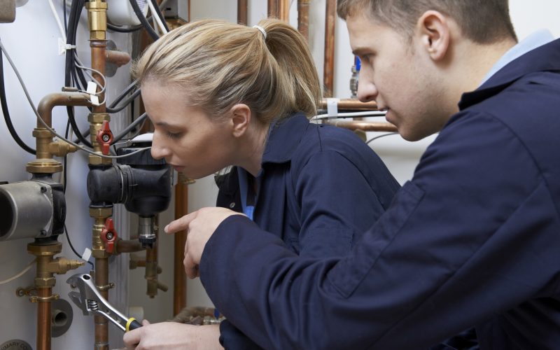 Female Trainee Plumber Working On Central Heating Boiler